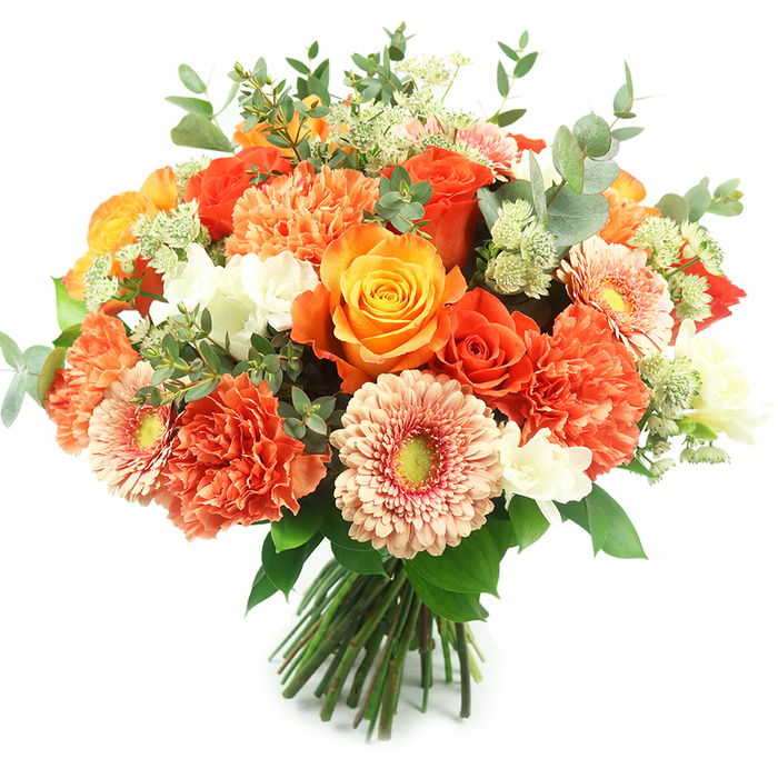 Presented upright against a pristine white field, this luxurious, bountiful bouquet combines warm, sunlit tones with layered botanical textures for an elegant, celebratory effect. Dominant in the arrangement are several richly coloured roses in shades from deep orange to golden yellow, their full, spiralled heads offering a classic, velvety focal point. Interspersed among them are abundant coral and burnt-orange carnations whose ruffled, multi-layered petals create substantial, soft volume. Light peach gerbera daisies emerge with broad, open faces and subtle yellow-green centres, introducing a cheerful, graphic rhythm to the bouquet's surface. Scattered white accent blooms - small and refined, like freesia or tiny spray carnations - provide crisp, luminous contrast, while pale-green, astrantia-like clusters add an intricate, feathery detail that invites closer inspection. The arrangement is threaded with generous eucalyptus stems; their rounded, grey-green leaves add cool depth, natural framing and a faint, aromatic lift that complements the sweeter blooms. The stems are tightly gathered and bound at the base in a professional hand-tied presentation, suggesting freshness straight from the cooler to the vase. As a florist attentive to the local character of Surrey Quays - from the calm promenades by Greenland Dock to the bustle near Surrey Quays Shopping Centre - I picture this bouquet as an elegant centrepiece for an intimate autumn dinner or a joyful gift delivered to mark a birthday or anniversary in the neighbourhood. The overall effect is warm, refined and tactile: colours that glow, textures you want to touch, and a scent profile that feels both celebratory and homey.