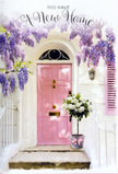 This evocative doorway scene in Surrey Quays feels like a quiet celebration of someone's first day in a new house. A pale pink front door, painted in a softly muted shade, stands as the welcoming centrepiece, its colour radiating gentle warmth against a backdrop of whitewashed walls and a single lightly painted shutter. From above, wisteria trails down in generous cascades, laden with clusters of lavender and lilac blossoms that drape like a floral curtain, suggesting a sweet, powdery fragrance hovering in the air. The sunlight is mellow, not bright, laying a soft glow across the door and stone step and creating delicate shadows in the folds of each drooping flower. At the doorstep sits a grey metal bucket carefully arranged by a skilled florist, filled to brimming with creamy white roses. Each rose appears full and velvety, with petals unfolding in tight spirals, intertwined with stems of fresh green foliage that add movement and contrast. A pink ribbon is tied around the bucket in a relaxed yet precise bow, repeating the gentle tones of the door and binding the entire scene in a cohesive pastel palette. The atmosphere feels quietly hopeful, as if this arrangement has just been delivered to mark a move into a flat near Greenland Dock or the riverside paths. The image suggests a thoughtful housewarming or congratulations gift, a floral gesture that makes crossing the threshold feel special, crafted with care by a local Surrey Quays florist attuned to the intimate, homely moments that flowers can transform.